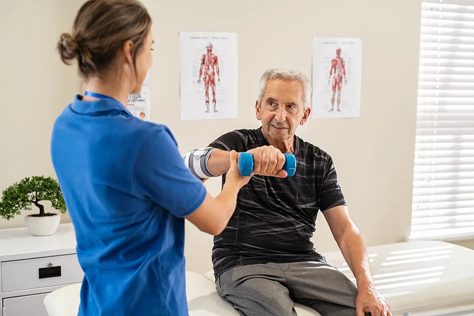 physiotherapist-helping-senior-man-exercise-2021-09-02-08-35-17-utc